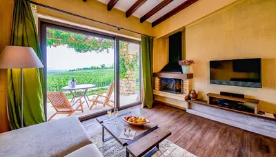 a living room with a fireplace and a large window at Zornitza Family Estate Relais & Chateaux in Melnik