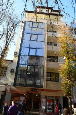a tall building with people walking in front of it at Main Street Apartment in Sandanski