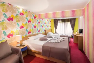 a hotel room with three beds and a couch at Hotel Central Point in Sofia