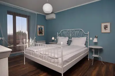 a bedroom with a white bed in a blue wall at Esterra Vini Guest House in Perushtitsa
