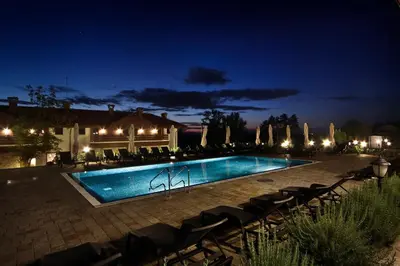 a swimming pool at night with chairs around it at Esterra Vini Guest House in Perushtitsa