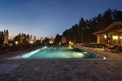 a swimming pool at night with lights on at Esterra Vini Guest House in Perushtitsa