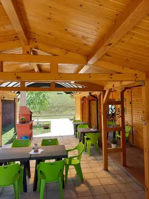 a wooden patio with tables and green chairs at Вилно селище МИРОВЕЦ in Malŭk Izvor