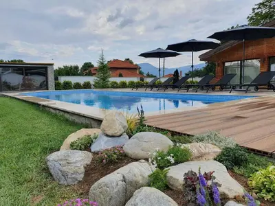 a swimming pool with rocks and umbrellas in a yard at Vila Antik in Garmen