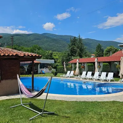 a pool with two hammocks and chairs next to a house at Вила Флора Паталеница in Patalenitsa