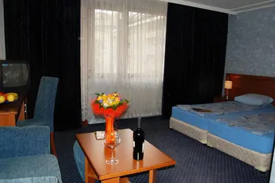 a hotel room with a bed and a table with flowers at Hotel Kibella in Sofia