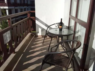 a table and chair on a balcony with a bottle of wine at Oksana's Apartment at Infinity in Bansko