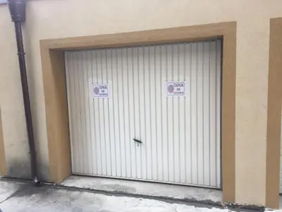 a white garage door with two signs on it at Pirotska Apartment GN / FREE GARAGE in Sofia