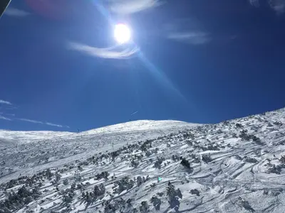 a snow covered mountain with the sun in the sky at Studio in Hotel Flora Borovets in Borovets