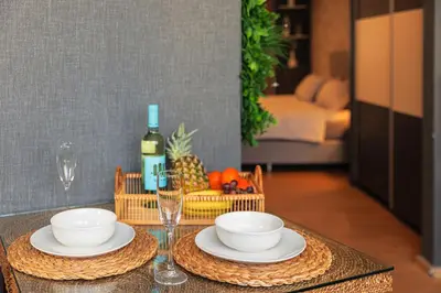 a table with plates and bowls and a bottle of wine at City Center Apartments with Parking in Plovdiv