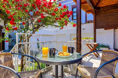 a table with a plate of food on a balcony with flowers at The House With The Piano in Plovdiv
