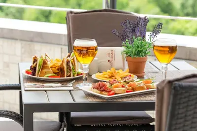 a table with two glasses of beer and a plate of food at Grami Hotel Sofia in Sofia