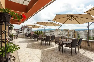 a patio with tables and chairs and umbrellas at Grami Hotel Sofia in Sofia