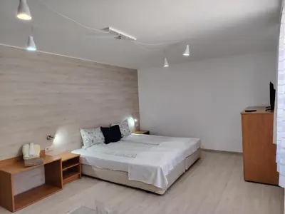 a white bedroom with a bed and a table at Guest House Lila in Bansko