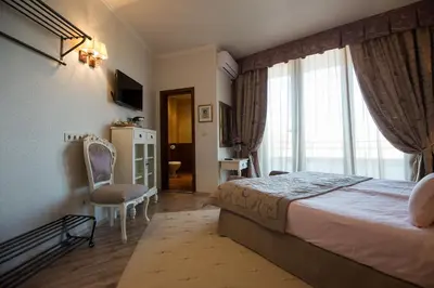 a bedroom with a bed and a window and a chair at Hotel Tempo Boutique in Pazardzhik