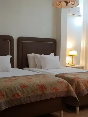 a bedroom with two beds and a lamp at Hotel Tempo Boutique in Pazardzhik