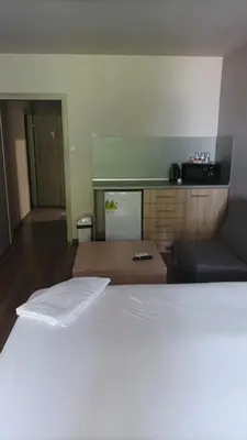 a bedroom with a white bed and a kitchen at Apartments KiM Sandanski in Sandanski