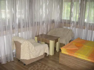a bedroom with a table and a bed and curtains at Guest House Lori in Teteven