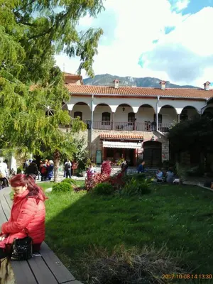 a woman sitting on a bench in front of a building at Vila Bachkovo in Bachkovo