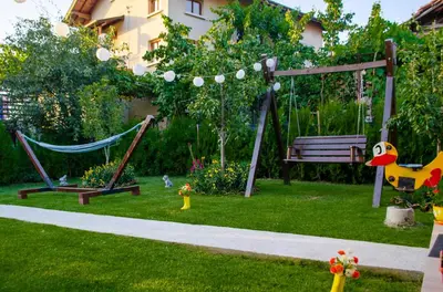 a playground with swings and a hammock in a yard at Guest House Vasilena Самостоятелно наемане FREE PARKING in Sapareva Banya