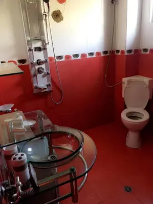 a red bathroom with a toilet and a glass sink at Guest House Pautalya in Kyustendil