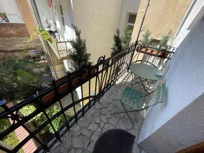 a balcony with a table and a chair next to a building at Time Traveling Apartment Sofia City in Sofia
