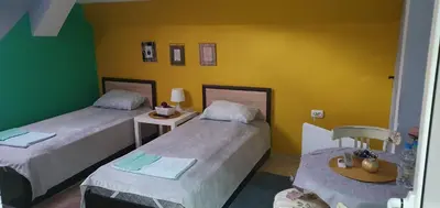 a room with two beds and a table and chairs at Rooms Lagat in Troyan