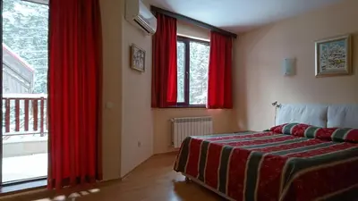 a bedroom with red curtains and a bed and a window at TES Flora Apartments in Borovets