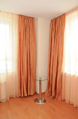 a room with orange curtains and a glass table at Hotel Astra in Sofia