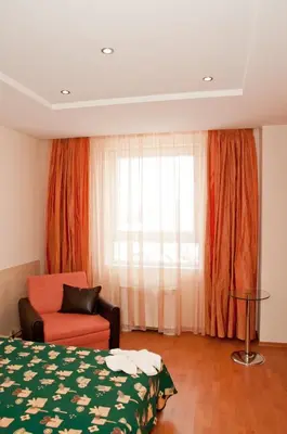 a bedroom with a bed and a chair and a window at Hotel Astra in Sofia