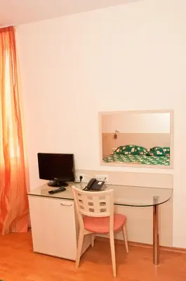 a desk with a computer and a chair in a room at Hotel Astra in Sofia