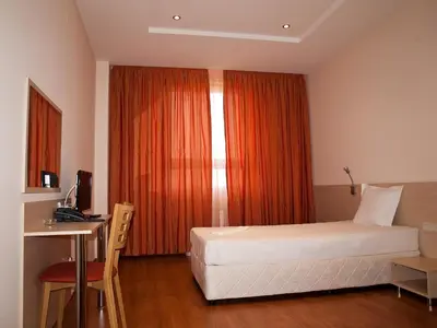a bedroom with a bed and a desk and a window at Hotel Astra in Sofia