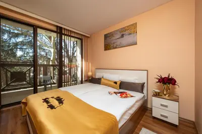 a bedroom with a bed with a yellow blanket and a window at MIDAS - Borov Park in Velingrad
