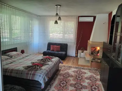 a bedroom with a bed and a chair and a fireplace at Guest House Lazar Raykov in Ribarica