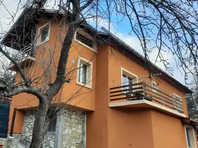 an orange building with a balcony and a tree at Guest House Lazar Raykov in Ribarica