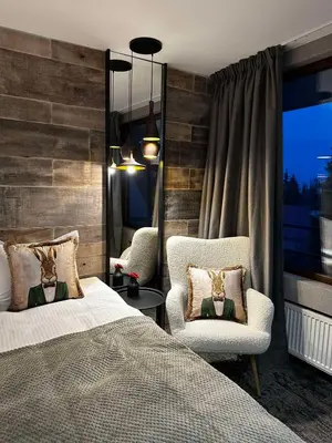 a bedroom with a bed and two chairs and a window at Grand Hotel Murgavets in Pamporovo