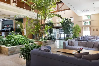 a lobby with couches and plants in a building at Pirin Park Hotel in Sandanski