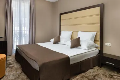 a bedroom with a large bed with a large headboard at Pirin Park Hotel in Sandanski