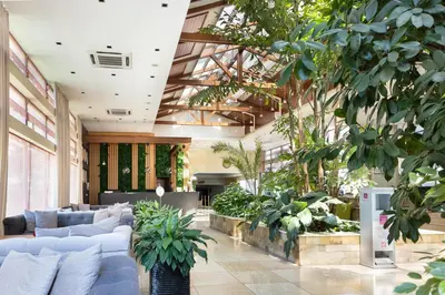 a lobby with couches and plants in a building at Pirin Park Hotel in Sandanski