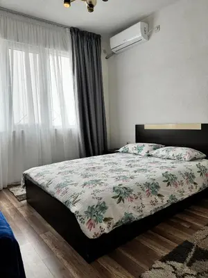 a bedroom with a bed with a floral comforter and a window at Apartment Alex in Sandanski