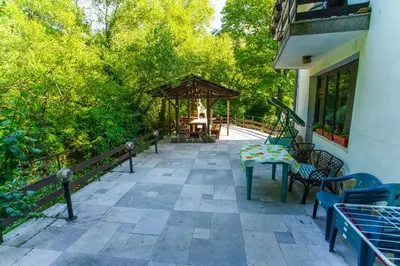a patio with a table and chairs and trees at Guest House Planinska Sreshta in Balkanets