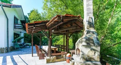a wooden pergola on a patio next to a house at Guest House Planinska Sreshta in Balkanets