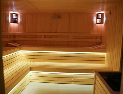 a sauna with wood paneling and lights in it at Flora Hotel - Apartments in Borovets