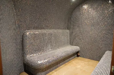 a bathroom with a bench in a tiled wall at Flora Hotel - Apartments in Borovets