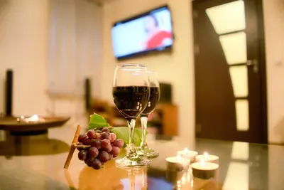 a glass of wine and grapes on a table at Guest House Villa Bozhenitsa in Bozhenitsa