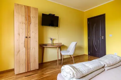 a bedroom with a bed and a table and a television at Guest House Villa Bozhenitsa in Bozhenitsa