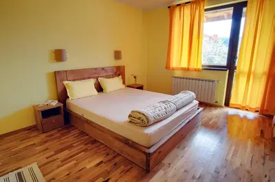 a bedroom with a bed and a window with yellow curtains at Guest House Villa Bozhenitsa in Bozhenitsa