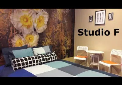 a bedroom with a bed and two chairs and flowers on the wall at Studio M in Plovdiv