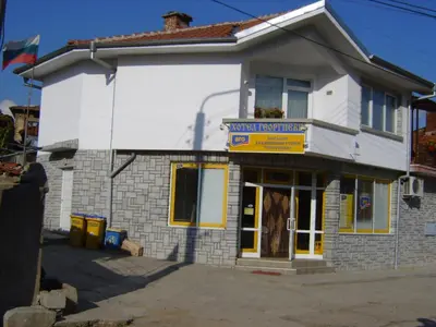 a white building with a sign on the front of it at Georgievi Guest House in Kalofer