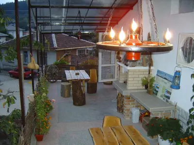 a patio with a bench and a table with lights at Georgievi Guest House in Kalofer